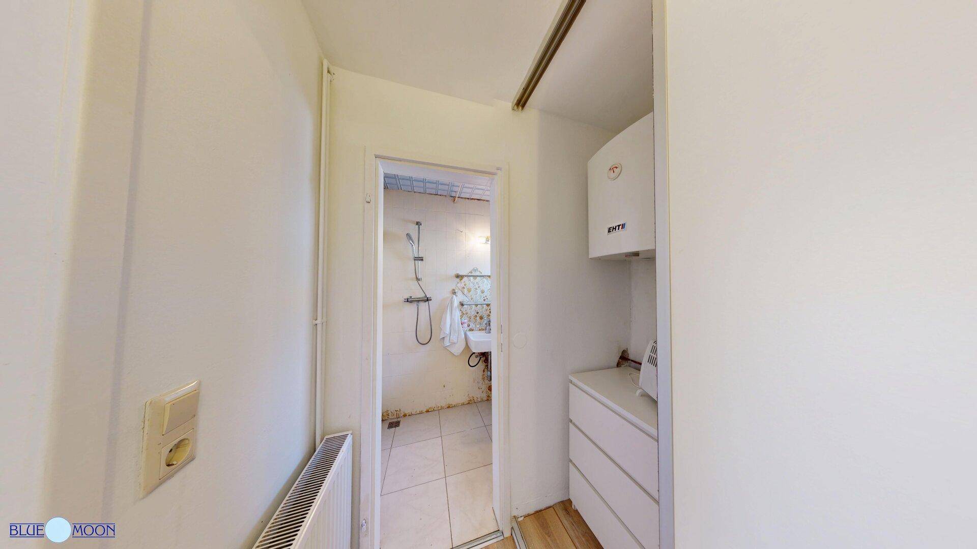 Kleines Badezimmer mit Dusche, Waschbecken und Warmwasserbereiter.