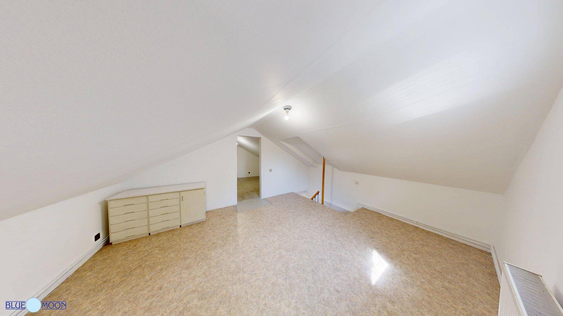 Heller Dachbodenraum mit schrägen Wänden und einem Schrank, ideal für Stauraum.