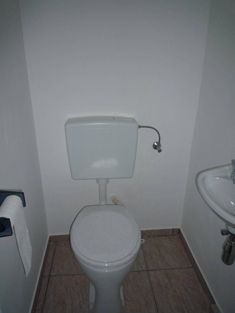 Kleines Gäste-WC mit Toilette, Waschbecken und Fliesenboden in neutralen Farbtönen.