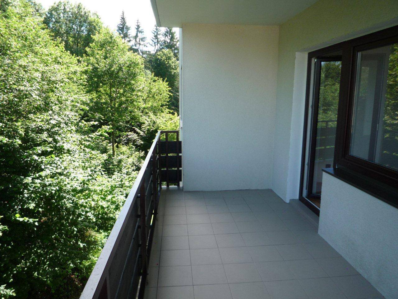 Heller Balkon mit Fliesenboden und weitem Blick auf die umliegende grüne Natur.