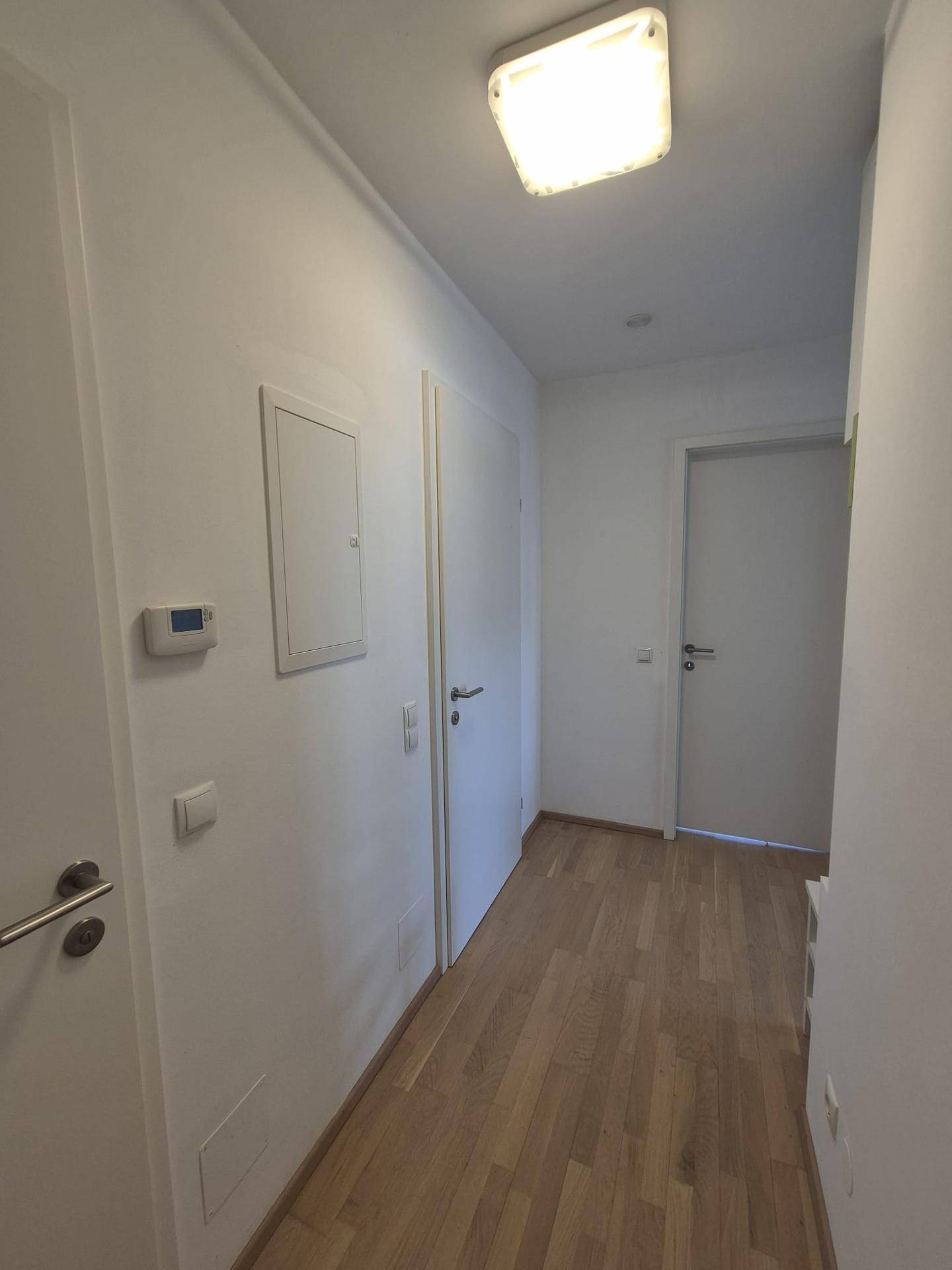 Langer, heller Flur mit Holzboden und mehreren Türen zu den Zimmern.