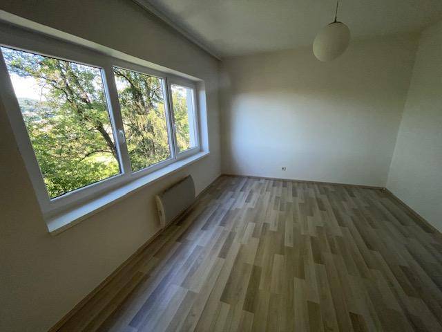 Lichtdurchflutetes Schlafzimmer mit Laminatboden und weitem Ausblick auf die umgebende Natur.