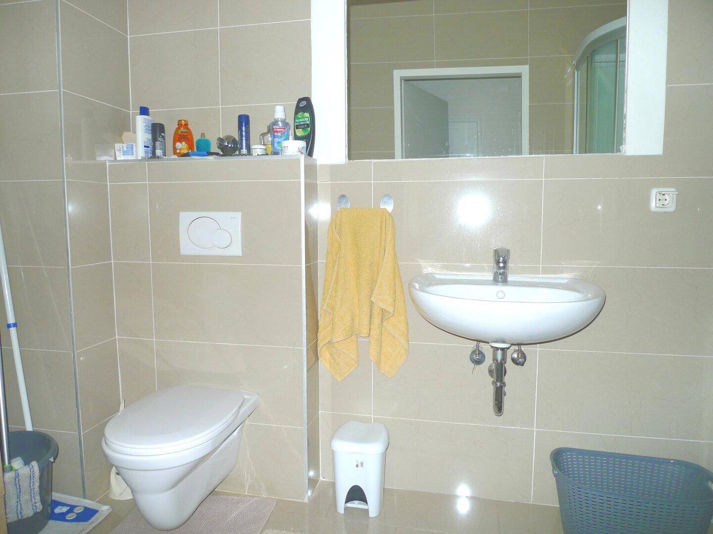 Modern gefliestes Badezimmer mit wandhängendem WC und Waschbecken.