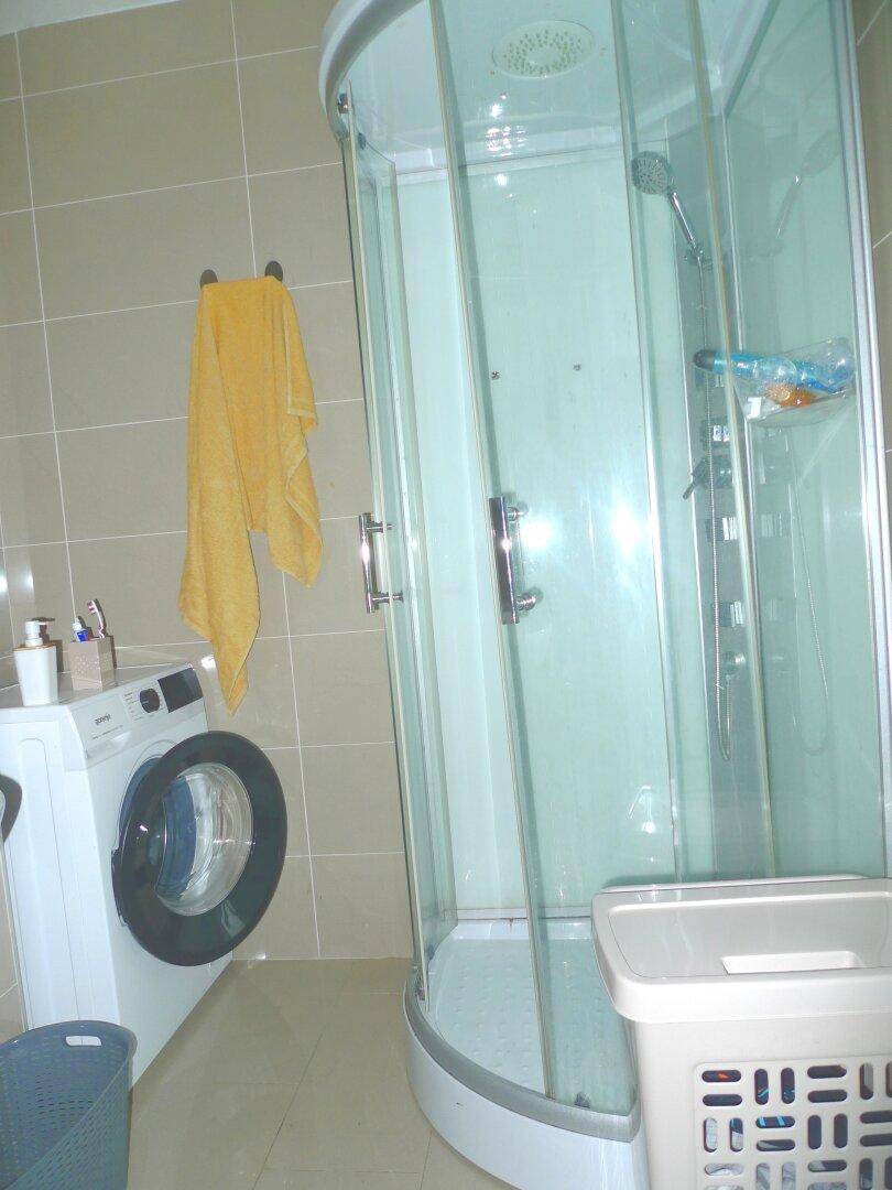 Badezimmer mit Duschkabine und Waschmaschine, praktisch und funktional eingerichtet.