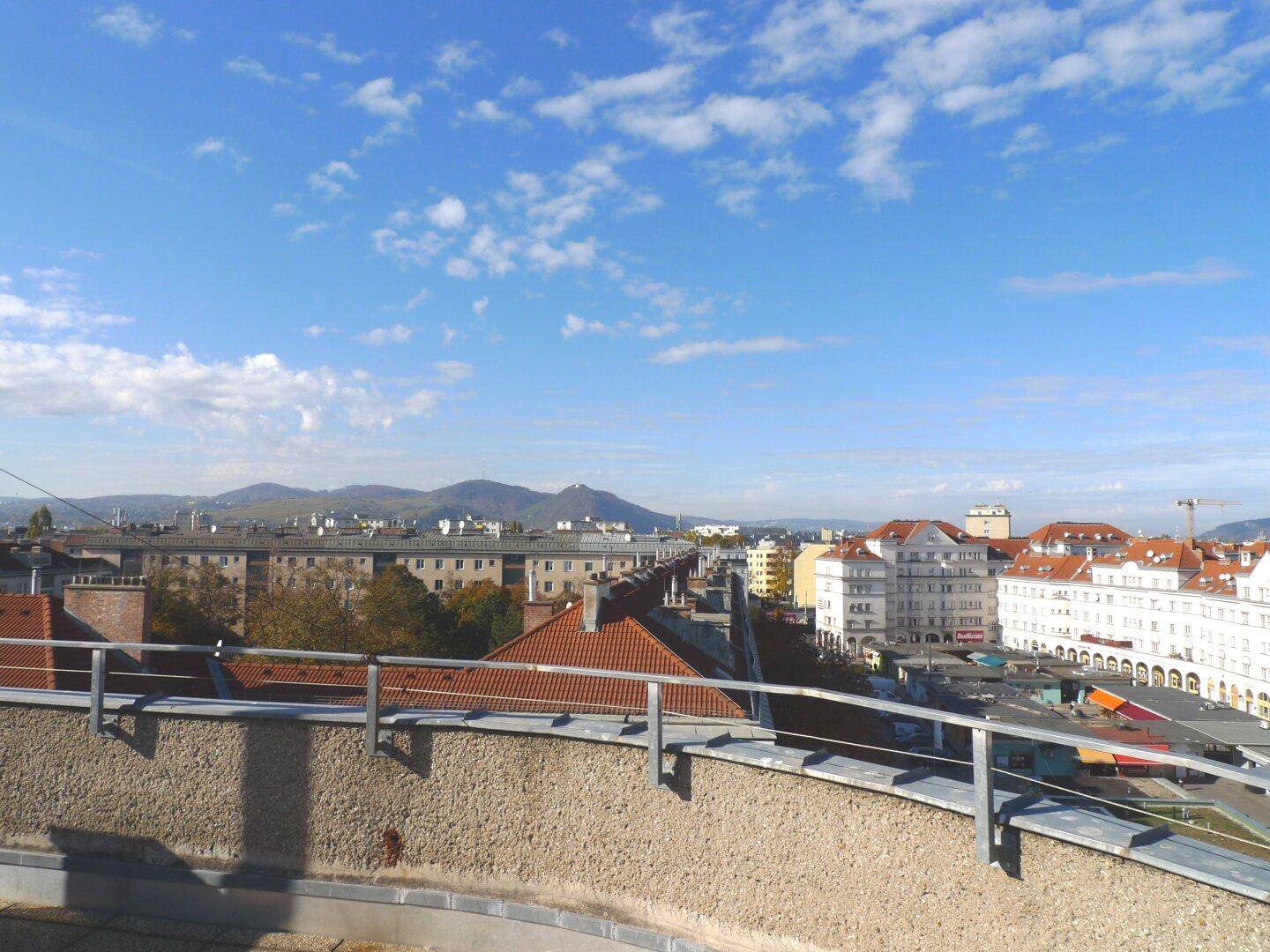 Panoramablick über die Stadtlandschaft mit blauem Himmel und fernen Bergen.