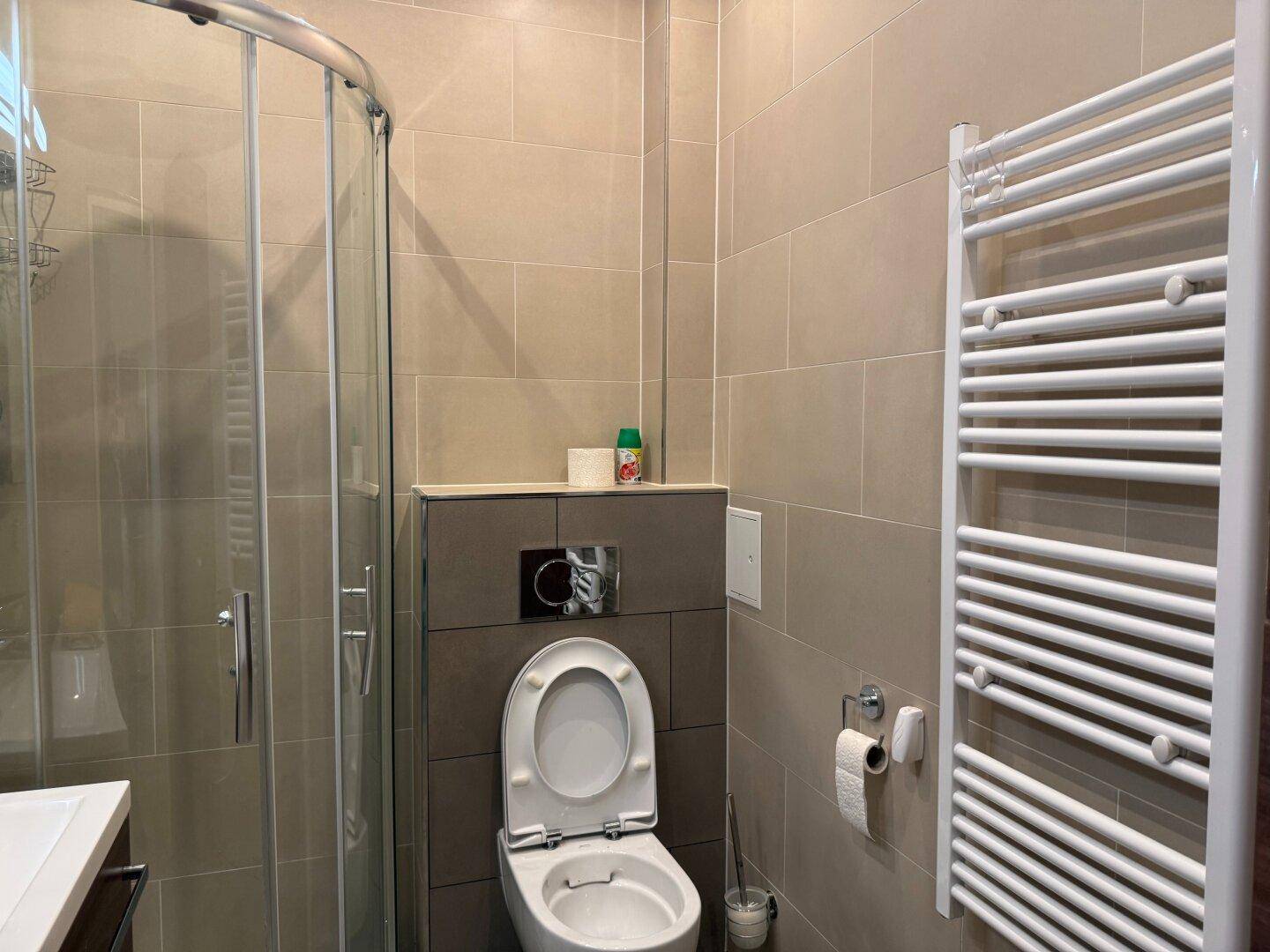 Funktionales Badezimmer mit wandhängendem WC und praktischem Handtuchheizkörper.
