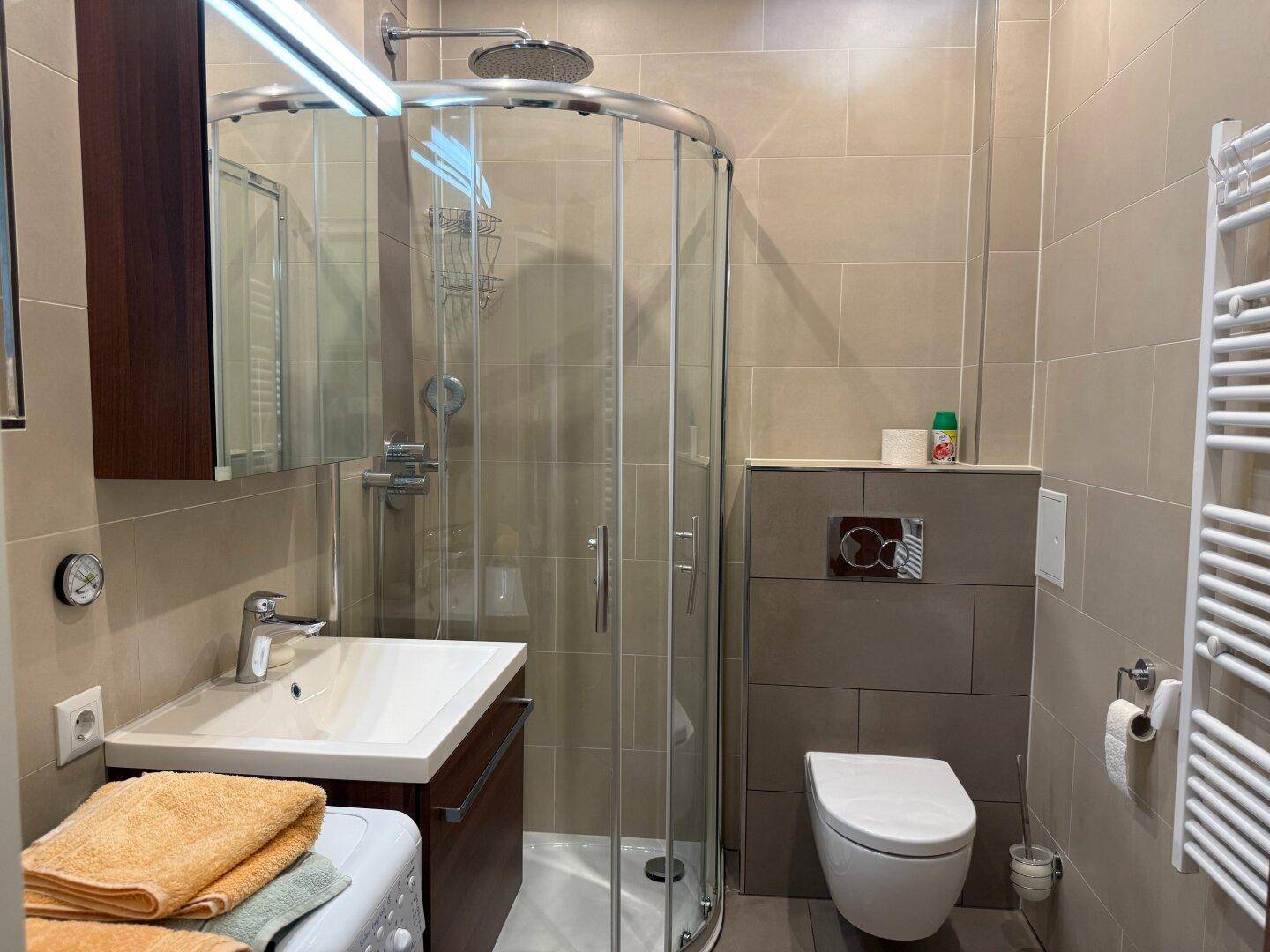Gepflegtes Badezimmer mit Duschkabine, WC und Waschtischunterschrank.
