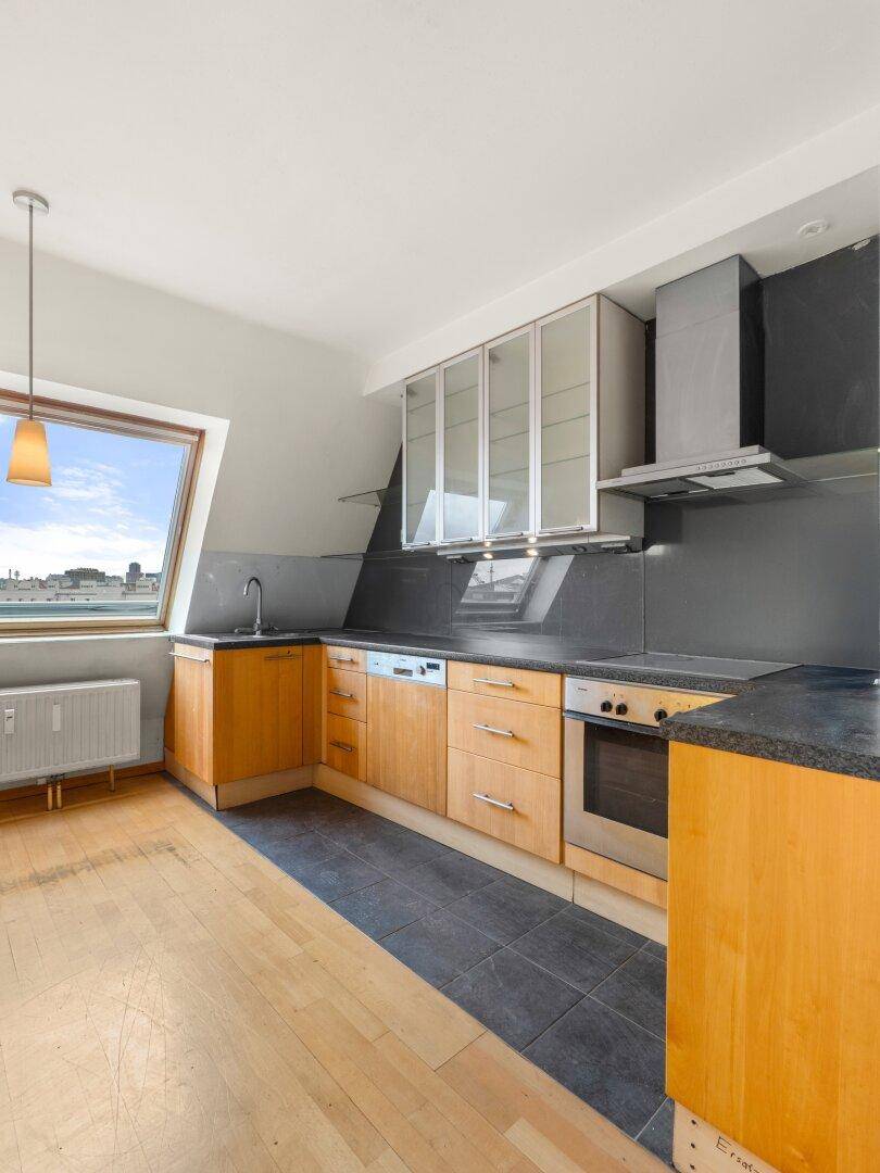 Helle Küche mit Dachfenster, Holzelementen und Blick auf die Stadtlandschaft.