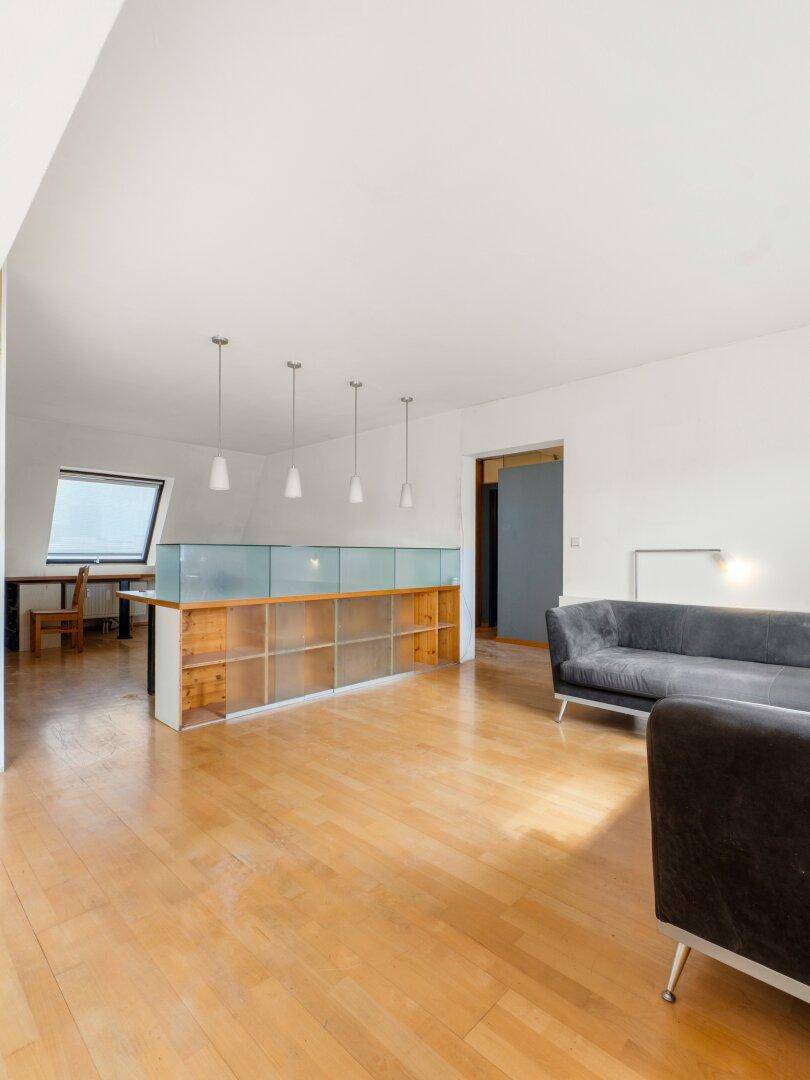 Helles Wohnzimmer mit Holzfußboden, modernem Sofa und einer Trennwand mit Glaselementen.