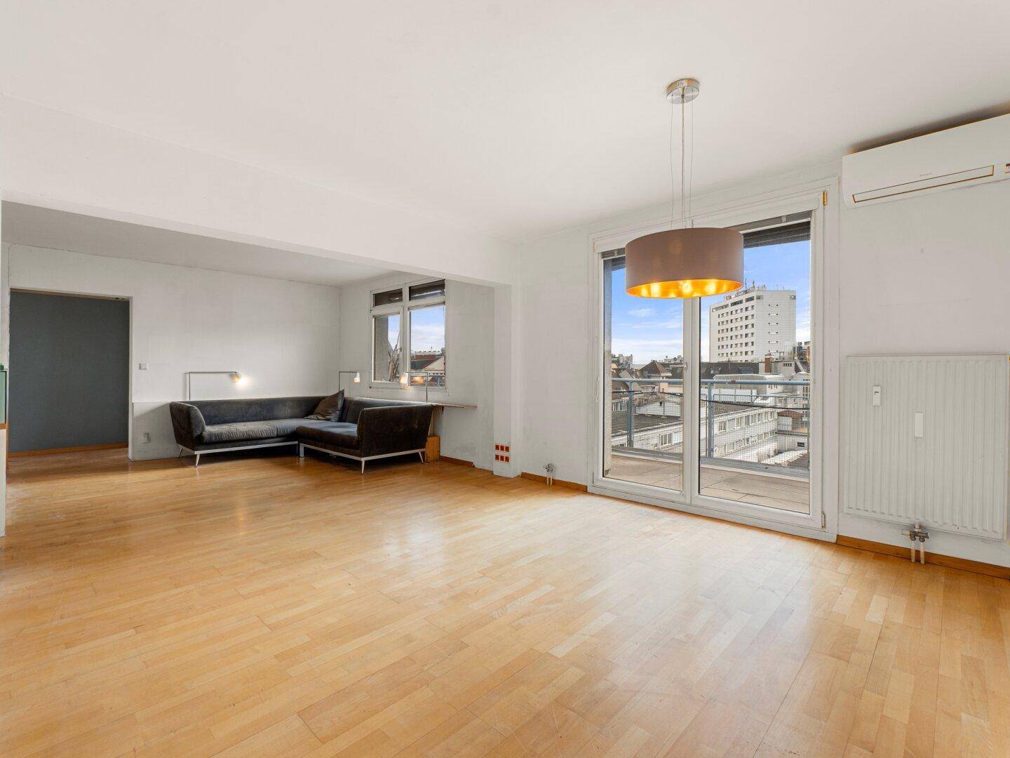 Geräumiges Wohnzimmer mit Holzfußboden, Balkonzugang und Klimaanlage, bietet Stadtblick.