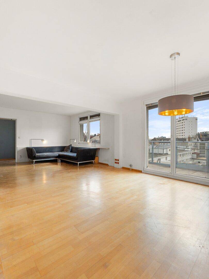 Großzügiges Wohnzimmer mit Holzfußboden, viel Tageslicht und direktem Zugang zum Balkon.