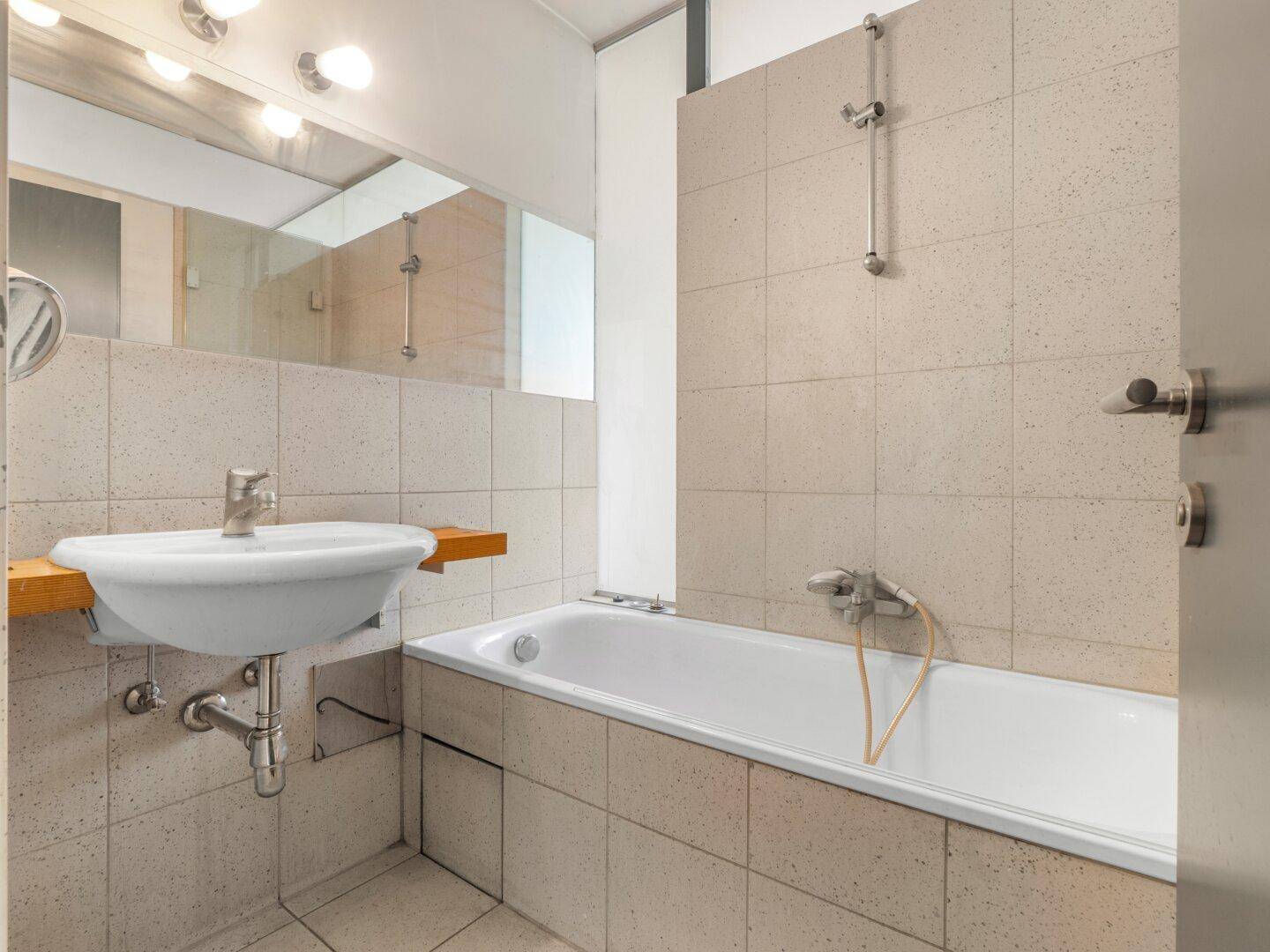 Funktionales Badezimmer mit Badewanne, Waschbecken und hellen Fliesen.