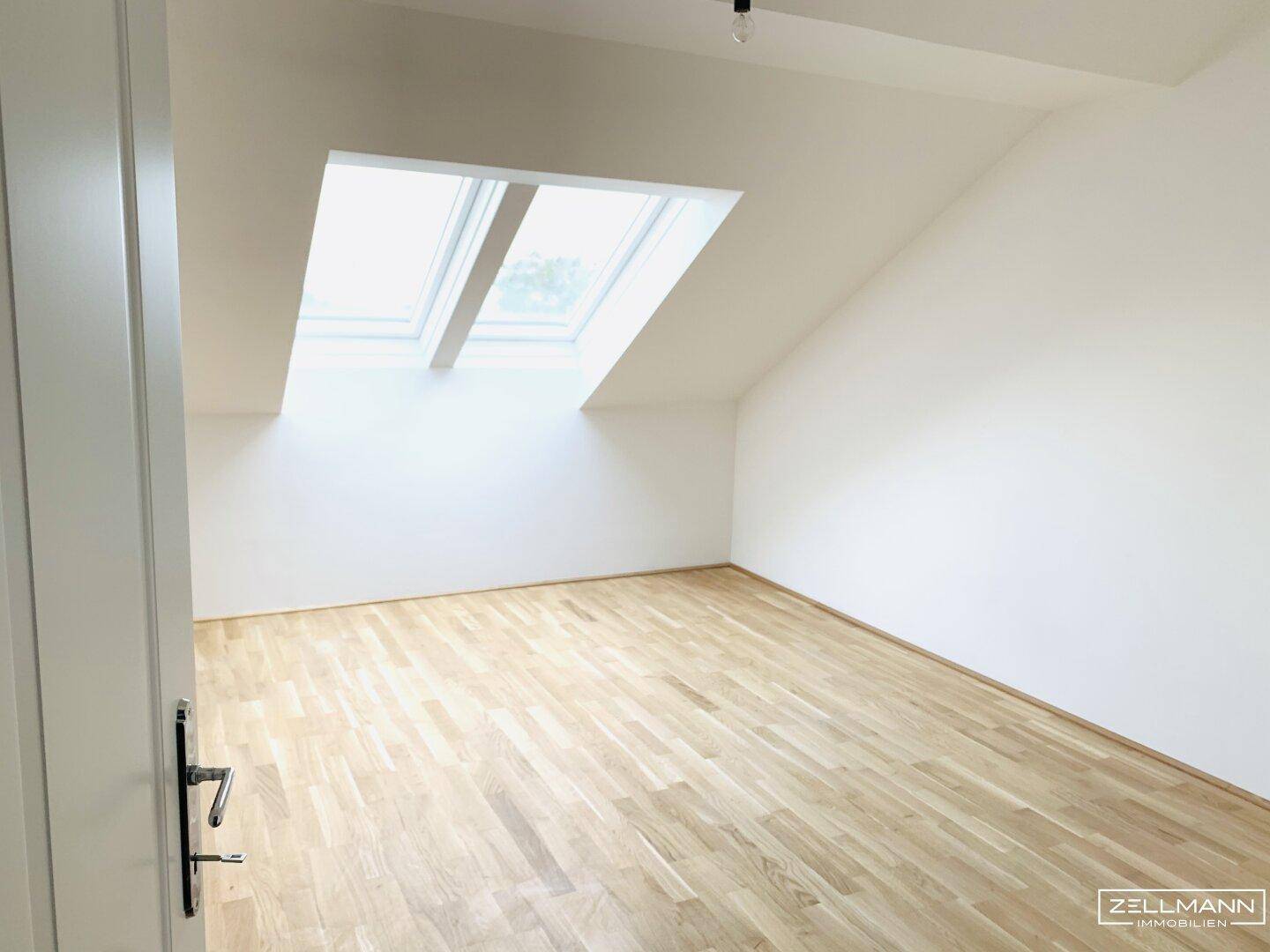 Helles Zimmer im Dachgeschoss mit Holzboden und zwei großen Dachfenstern, ideal als Schlaf- oder Arbeitszimmer.