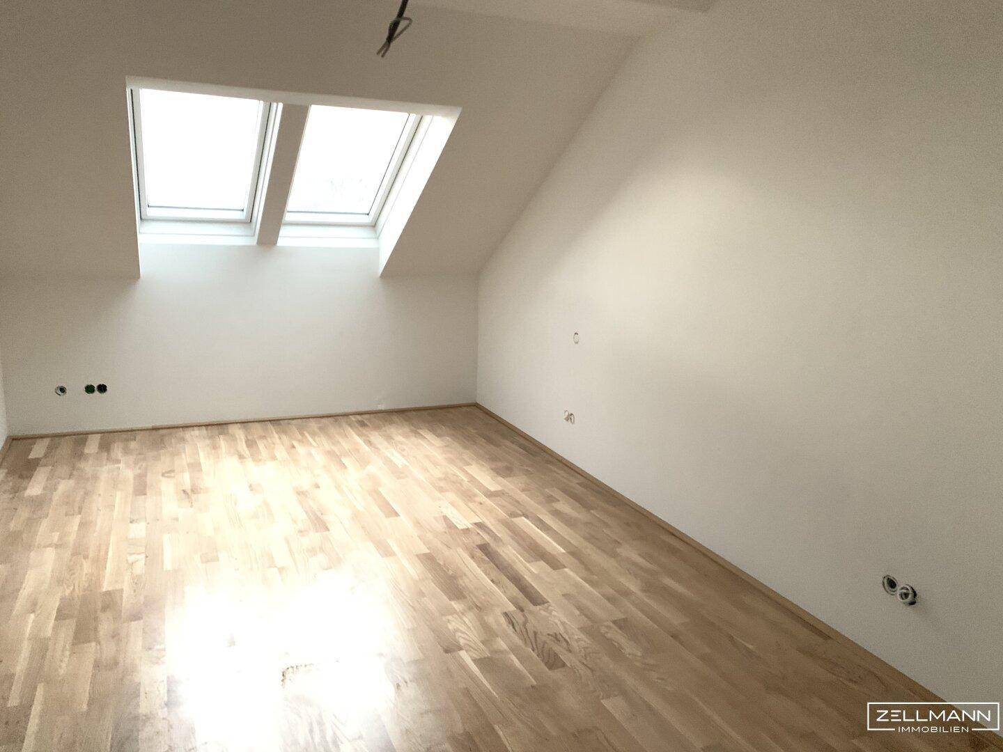 Geräumiges Dachgeschosszimmer mit hellem Holzboden und zwei großen Dachfenstern, bereit zum Einzug.