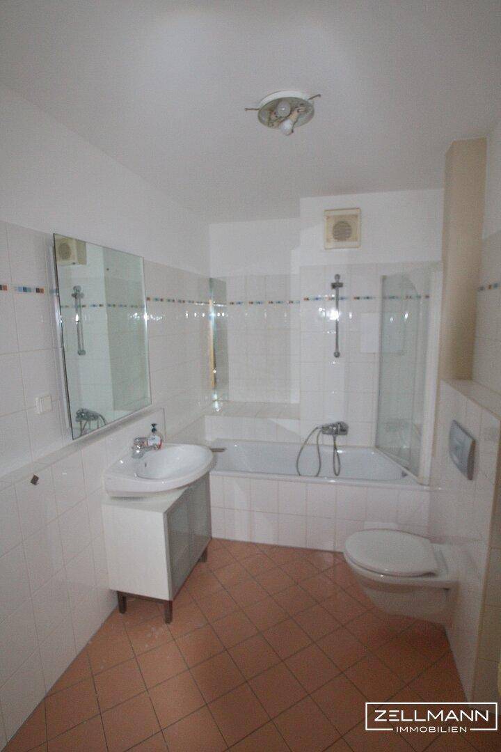 Helles Badezimmer mit Badewanne, Dusche, WC, Waschbecken und Spiegelschrank, gefliest in Weiß und Terrakotta.