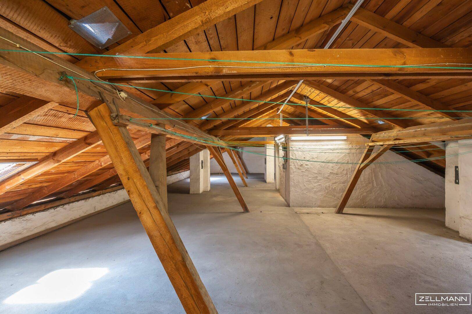 Heller Dachboden mit freiliegenden Holzbalken und einem Dachfenster, ideal für Ausbau.