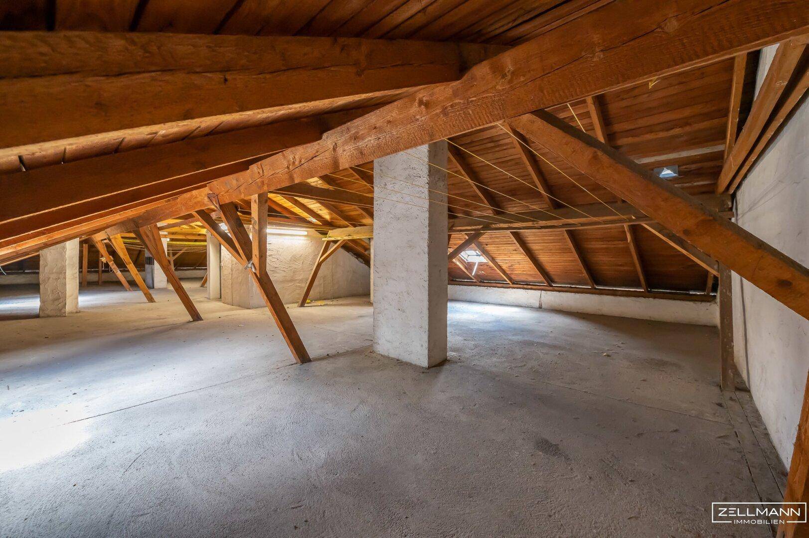 Geräumiger Dachboden mit sichtbaren Holzbalken und schrägen Wänden, ideal für zukünftigen Ausbau.