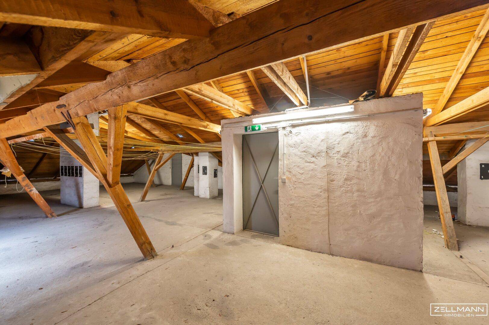 Dachboden mit freiliegenden Holzbalken und einem Aufzug, der den Zugang zum Dachgeschoss ermöglicht.