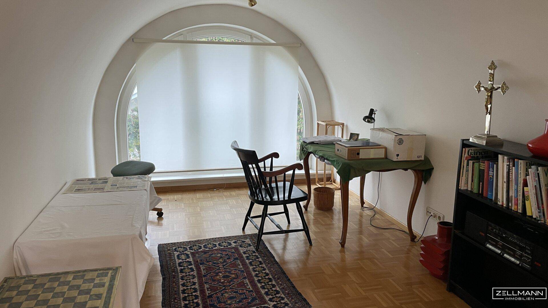Ruhiges Arbeitszimmer mit Parkettboden und einem einzigartigen Bogenfenster.