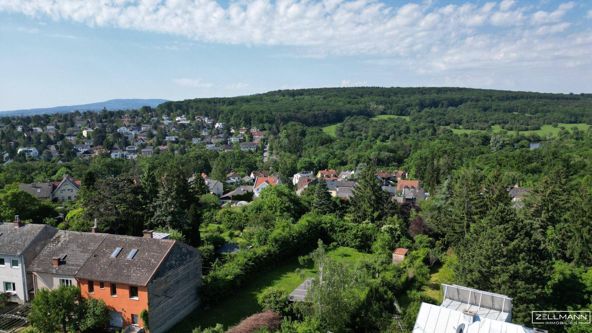 Weitläufige Wohngegend mit vielen Bäumen und Blick auf die umliegende Naturlandschaft.
