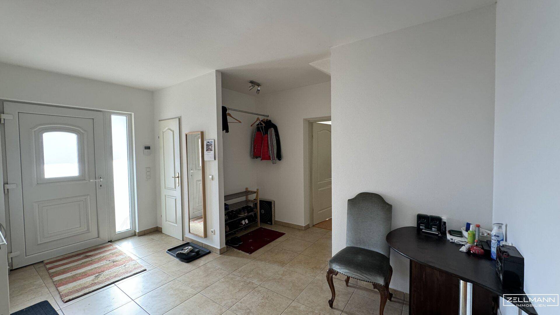 Heller Eingangsbereich mit Fliesenboden, Garderobe und Zugang zu weiteren Räumen.