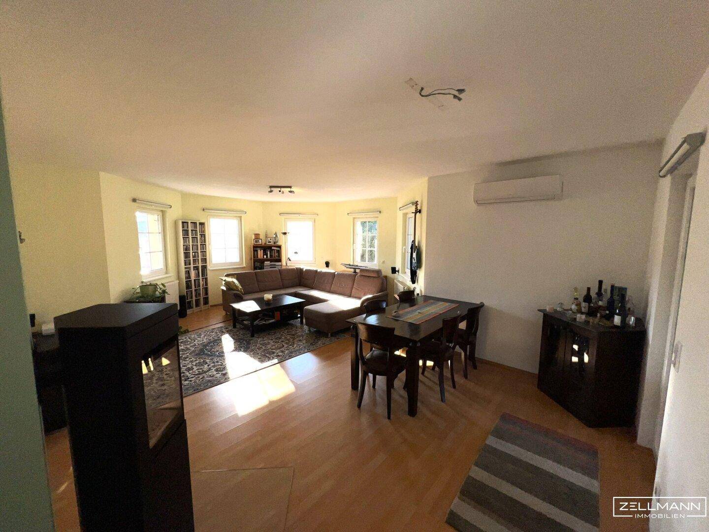 Lichtdurchfluteter Wohn- und Essbereich mit Parkettboden und Klimaanlage, ideal für Familienleben.