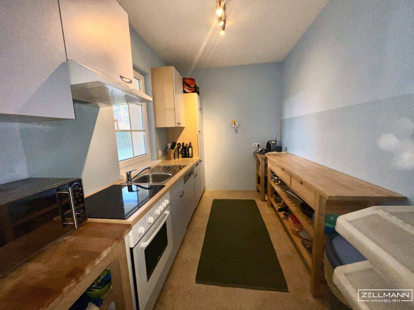 Funktionale Küche mit Einbaugeräten, Holztheke und Fenster für natürliches Licht.