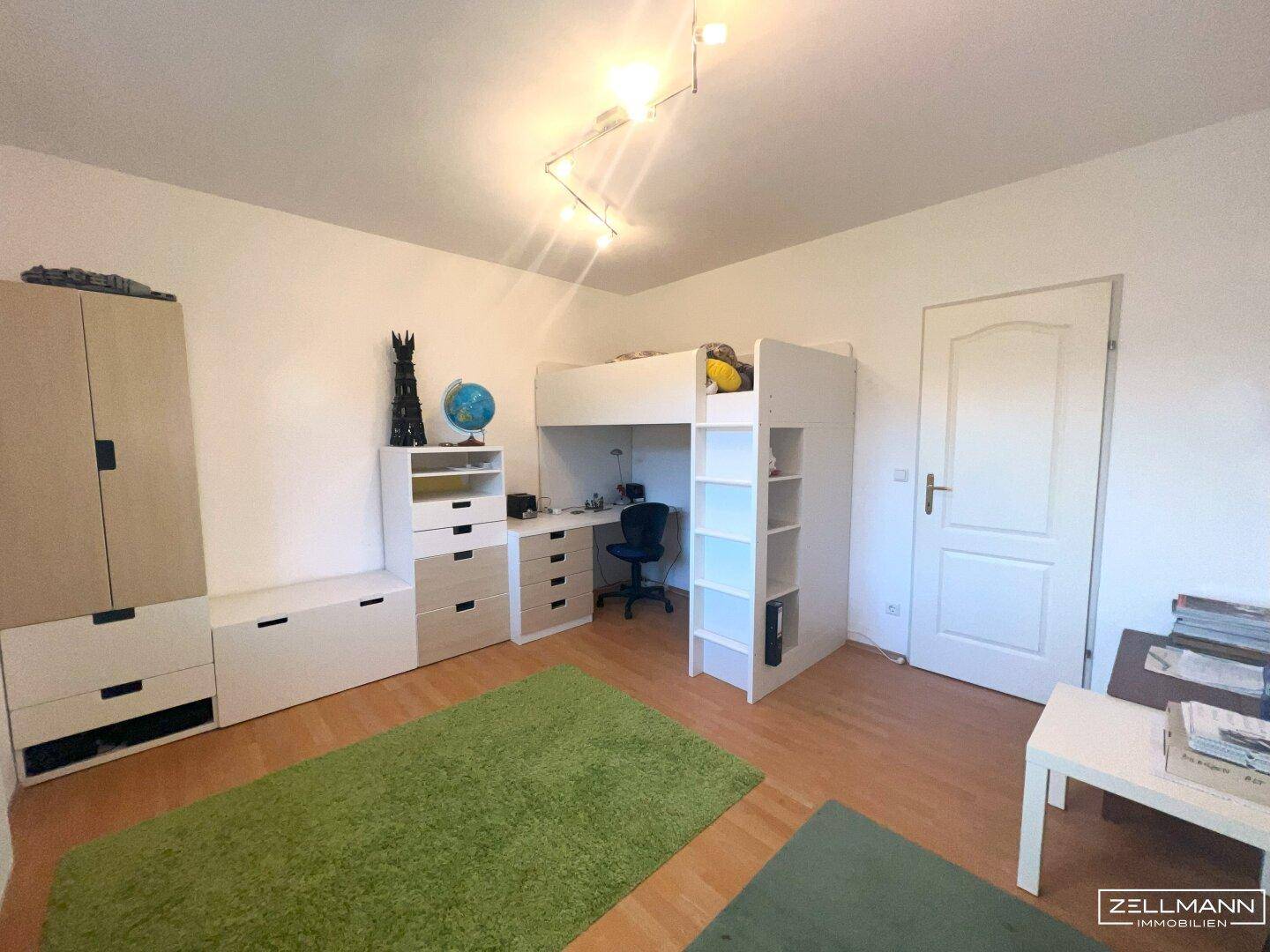 Kinderzimmer mit Hochbett, Schreibtisch und Schränken, bietet viel Platz zum Spielen und Lernen.