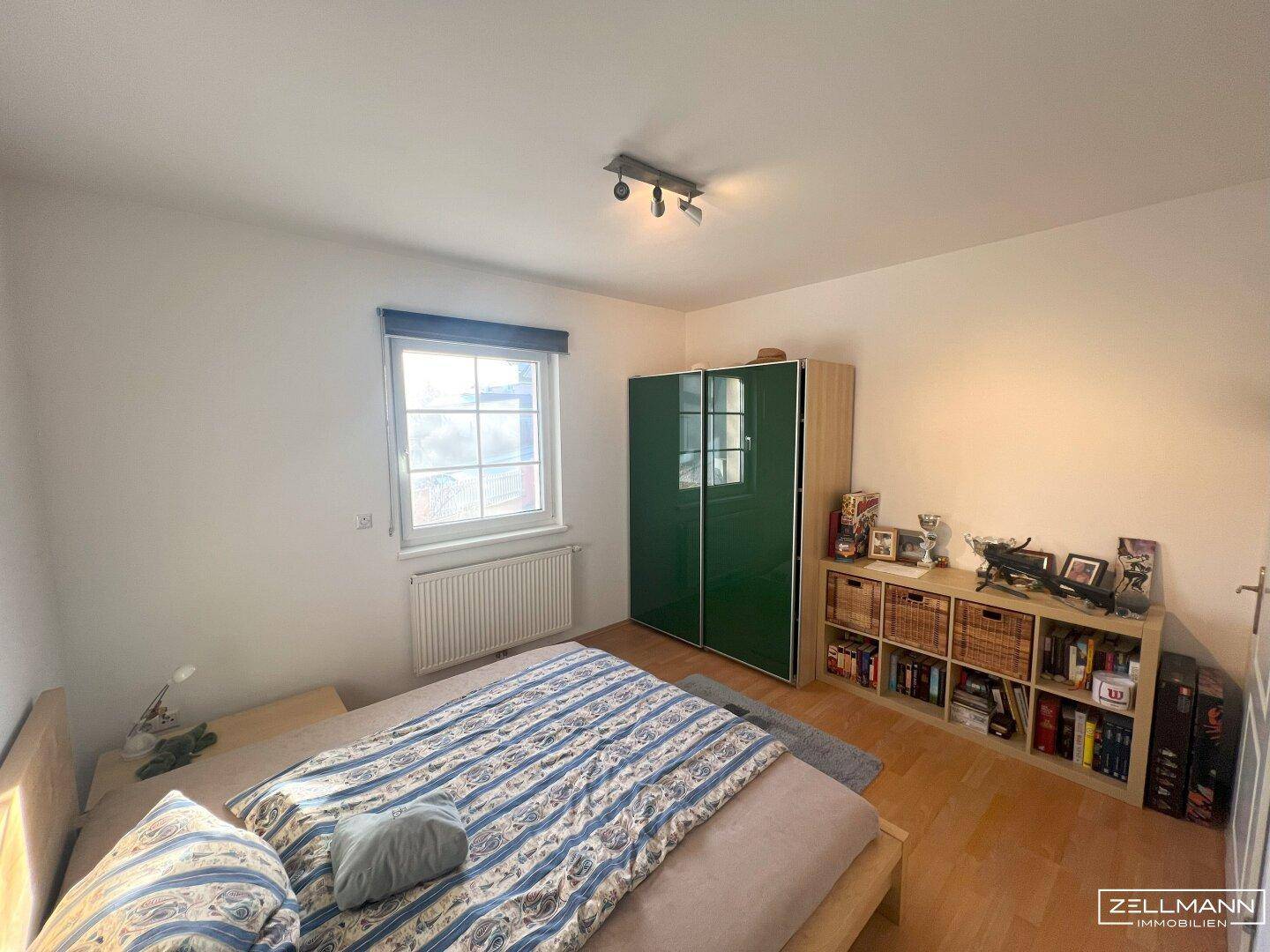 Schlafzimmer mit Doppelbett, Holzboden und grünem Kleiderschrank, bietet eine angenehme Atmosphäre.