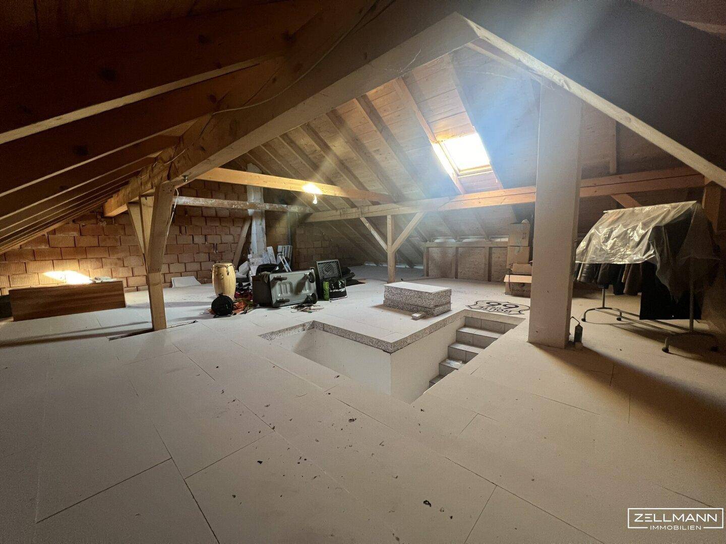 Ausbaufähiger Dachboden mit sichtbaren Holzbalken und Dachfenster, bietet viel Potenzial.