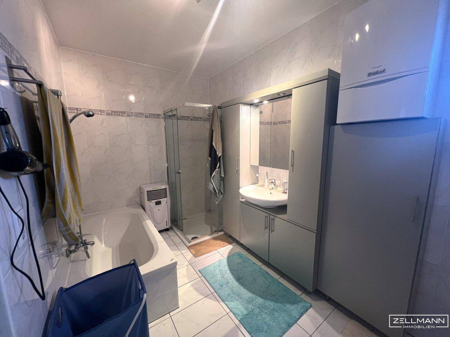 Badezimmer mit Badewanne, Dusche und Waschbecken, ausgestattet mit modernen Armaturen.