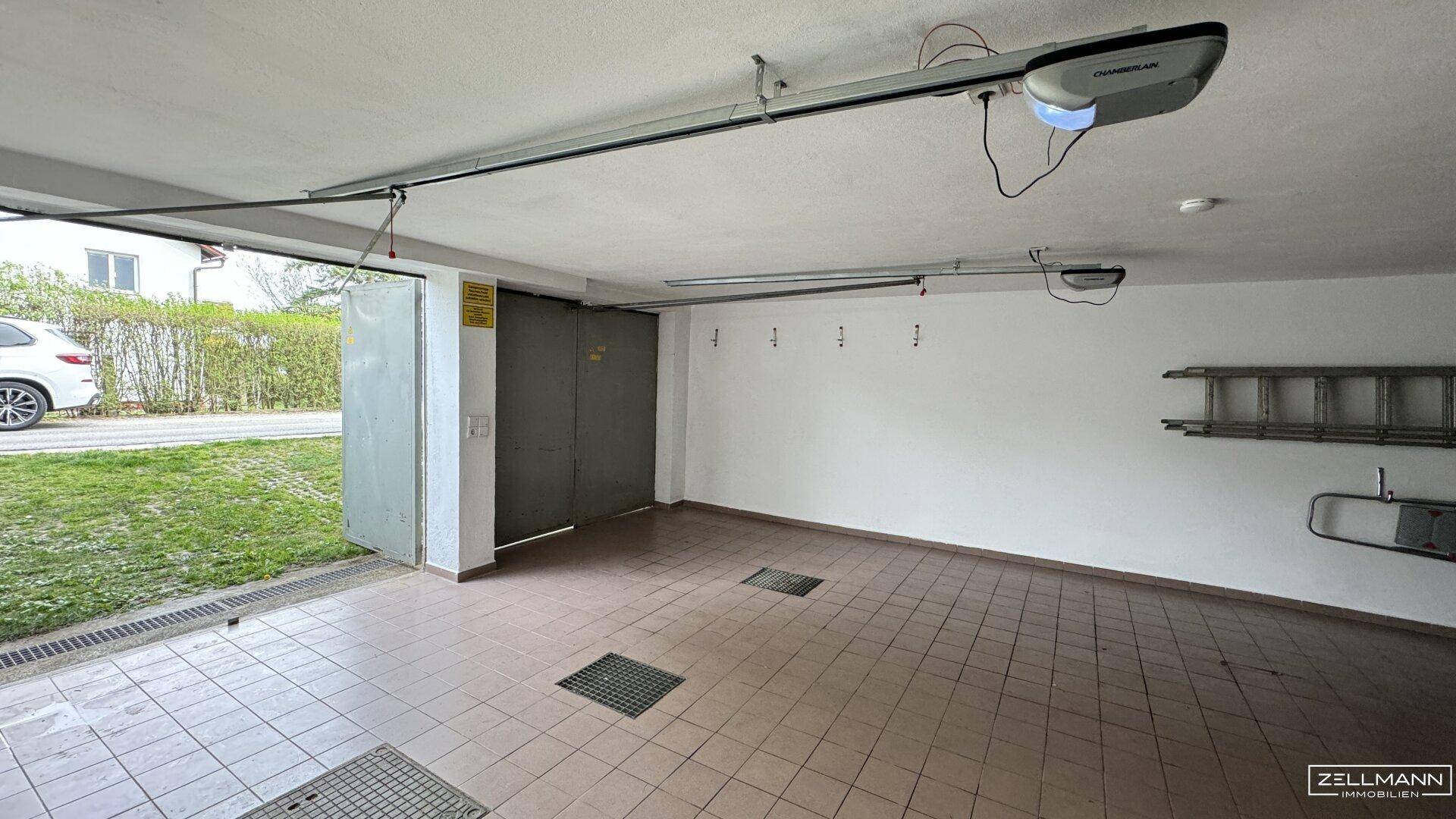 Geräumige Garage mit Fliesenboden, automatischem Torantrieb und direktem Zugang zur Straße.
