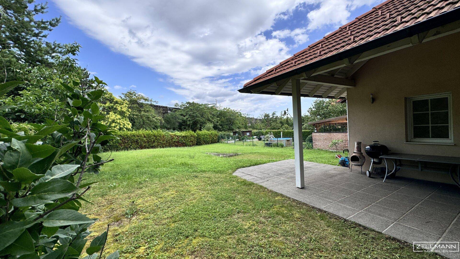 Großer Garten mit Rasenfläche und kleiner Terrasse, ideal für Outdoor-Aktivitäten und Entspannung.