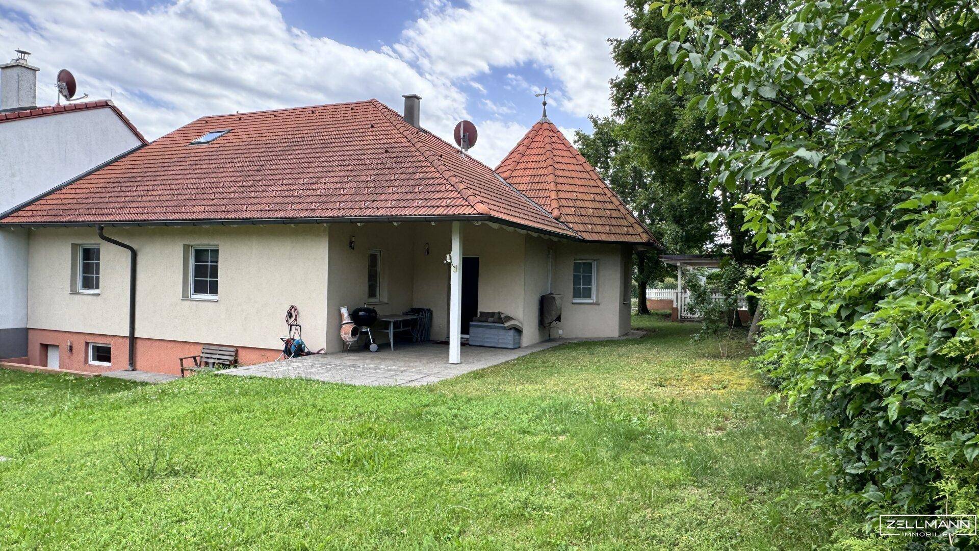 Rückseite des Hauses mit großer Rasenfläche, Terrasse und Grillbereich im Grünen.