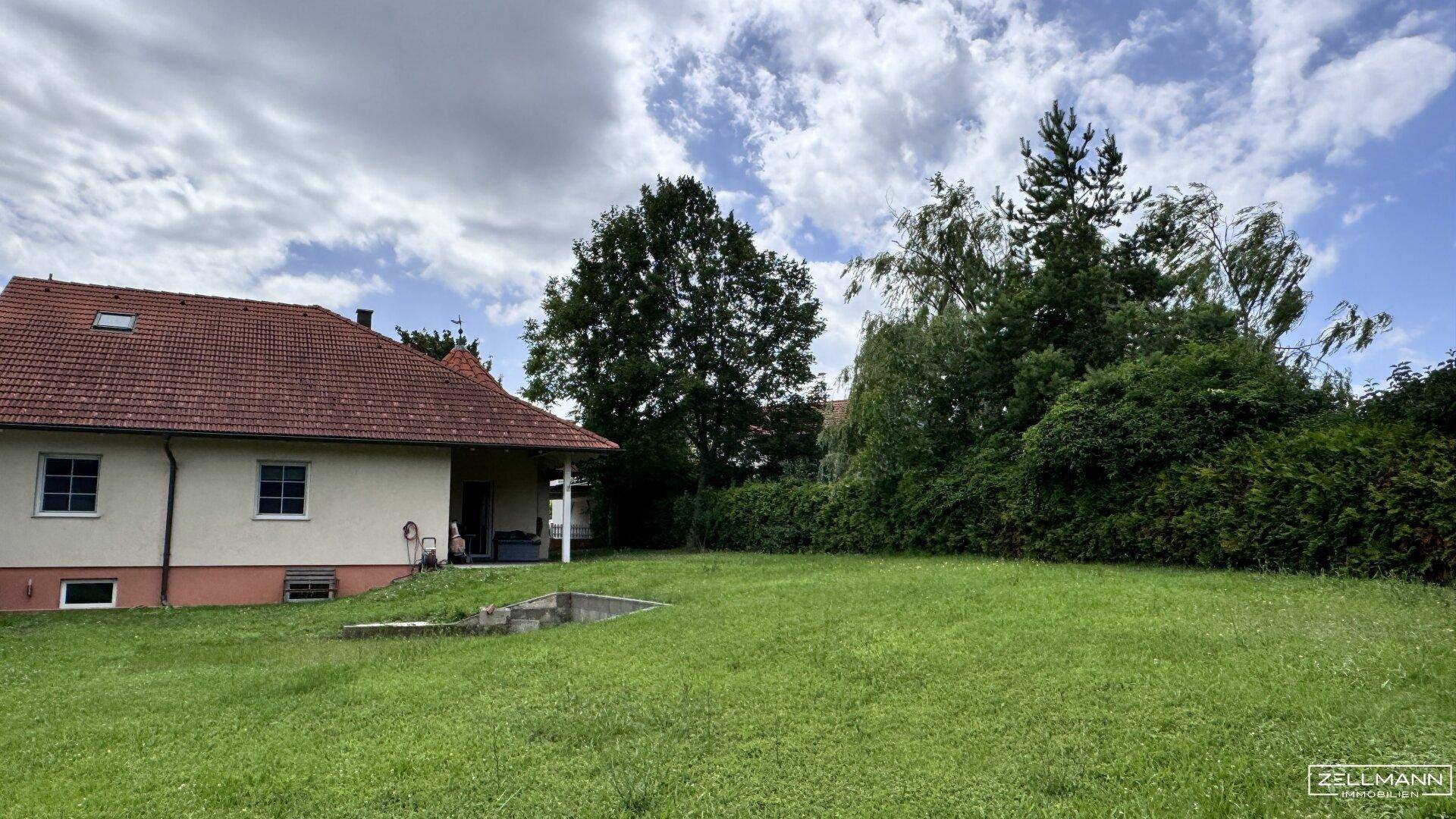 Weitläufiger Garten mit großer Rasenfläche und Bäumen im Hintergrund, bietet viel Platz im Freien.