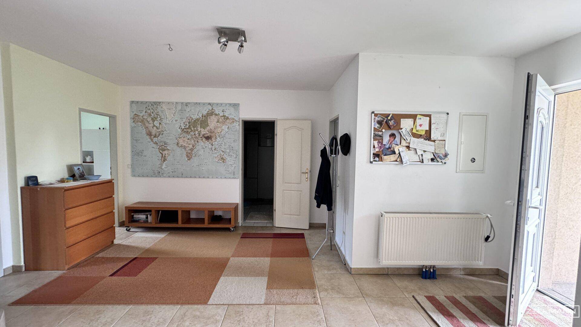 Heller Eingangsbereich mit Fliesenboden, Garderobe und einer Weltkarte an der Wand.