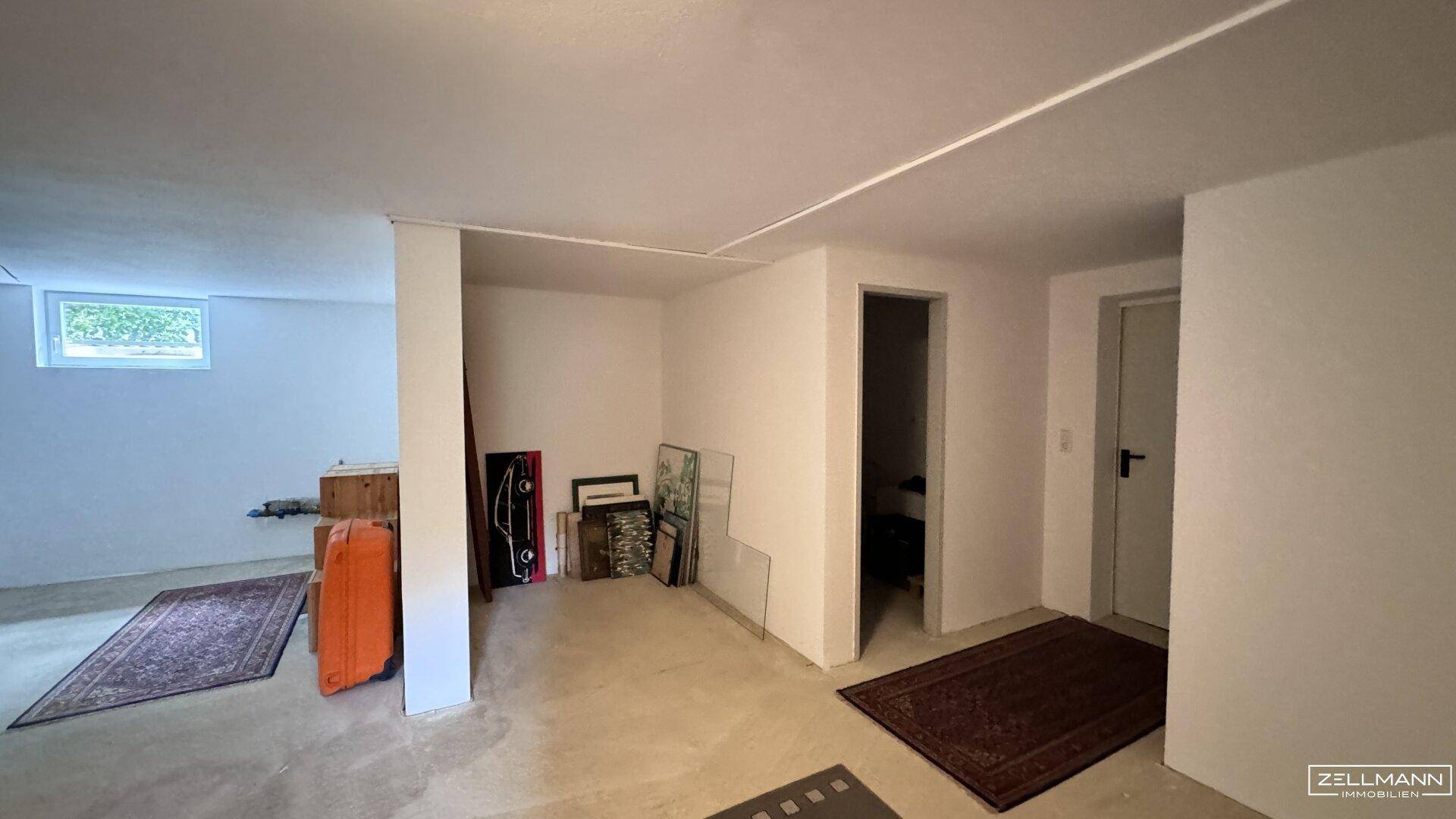 Geräumiger Kellerraum mit Betonboden und einem kleinen Fenster, ideal als Abstellfläche.