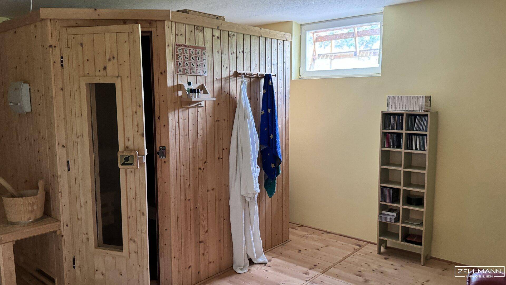 Wellnessbereich im Keller mit einer holzvertäfelten Sauna und einem kleinen Fenster.
