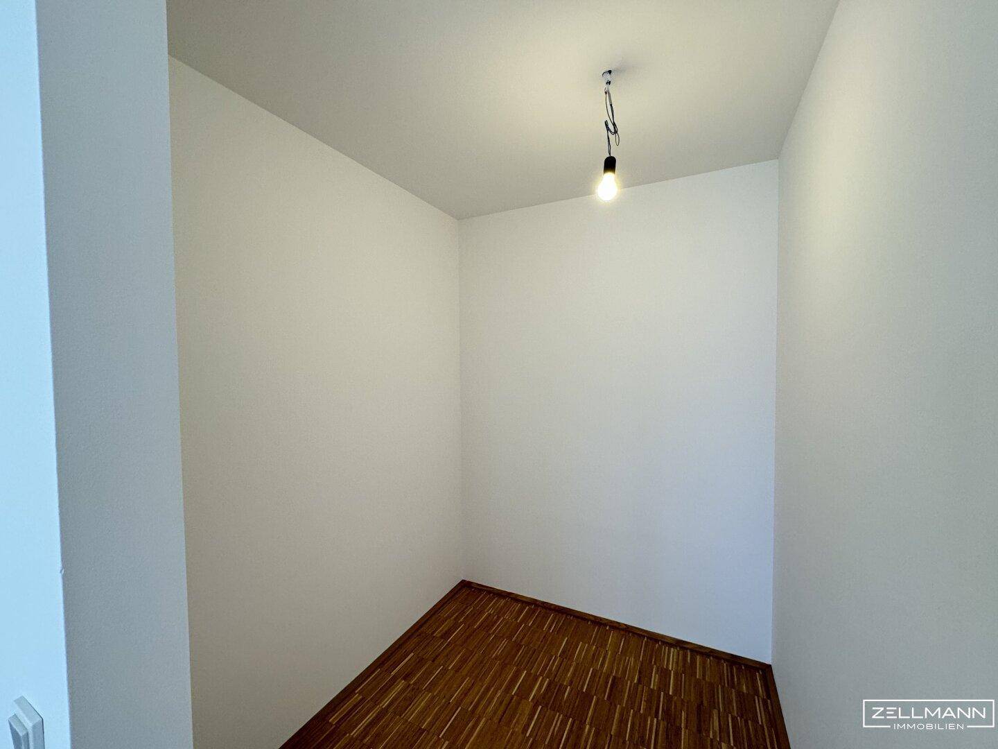 Kleiner, leerer Raum mit Laminatboden und weißen Wänden, ideal als Abstellkammer.