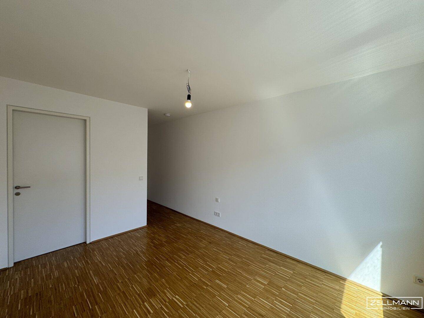 Leerer Raum mit Laminatboden und weiß gestrichenen Wänden, ideal für individuelle Gestaltung.