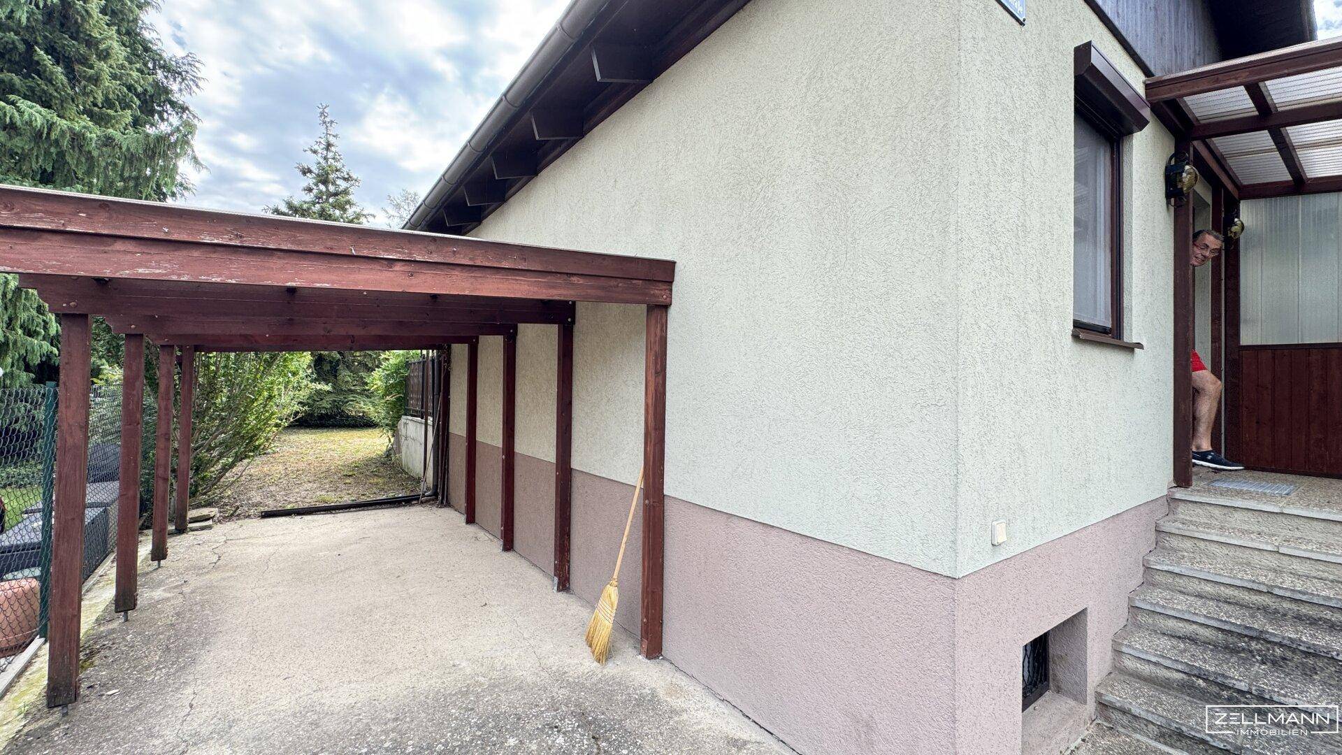 Seitenansicht des Hauses mit einem Holzcarport und einer Außentreppe zum Eingangsbereich.