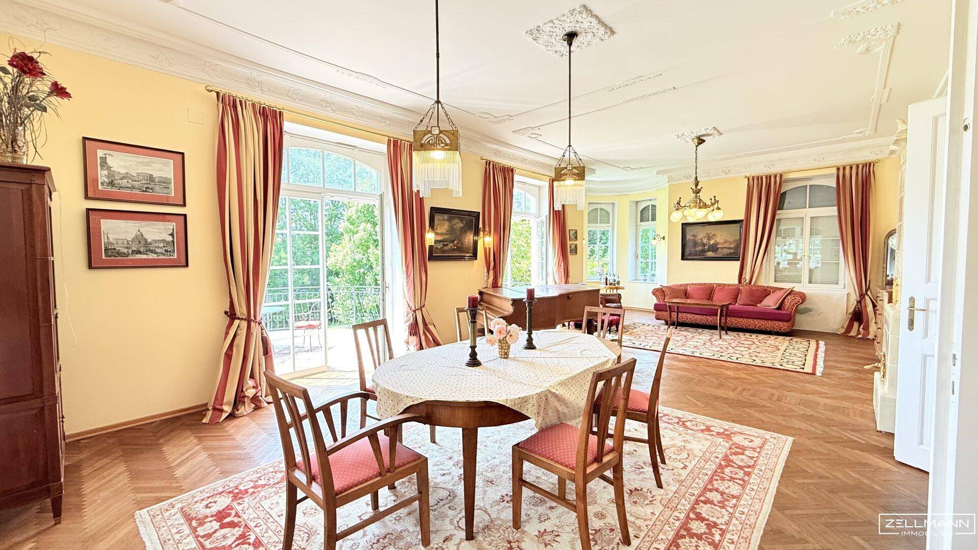 Repräsentativer Wohn- und Essbereich mit Parkettboden, Stuckdecken und Zugang zum Balkon.
