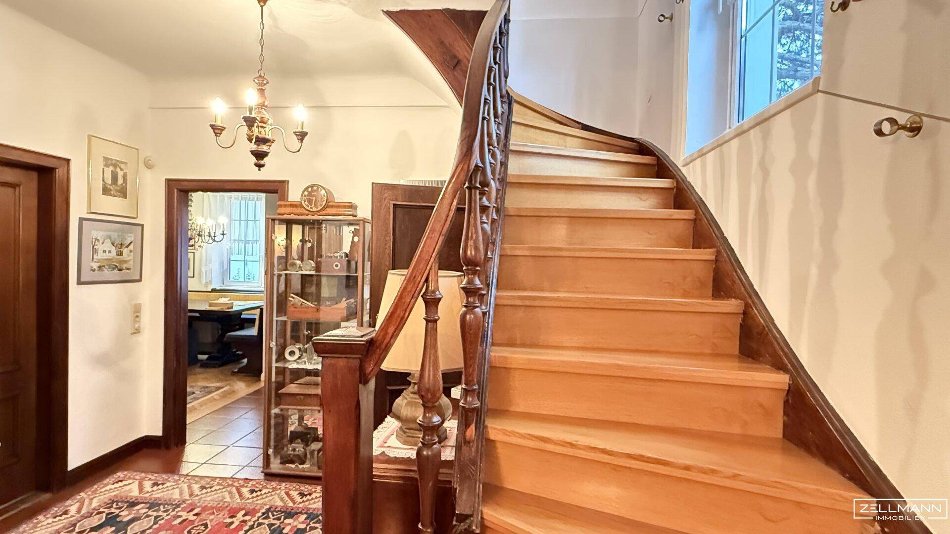 Elegante Holztreppe im Flur, die in die oberen Stockwerke führt, mit Blick auf weitere Räume.