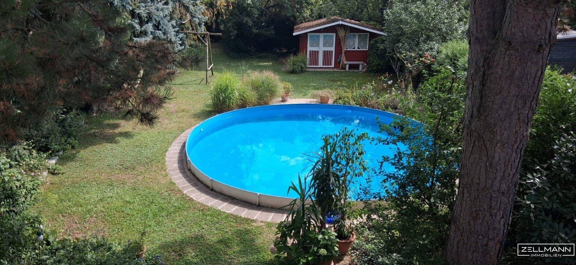 Großer Garten mit einem runden Aufstellpool, umgeben von Rasenflächen und altem Baumbestand.