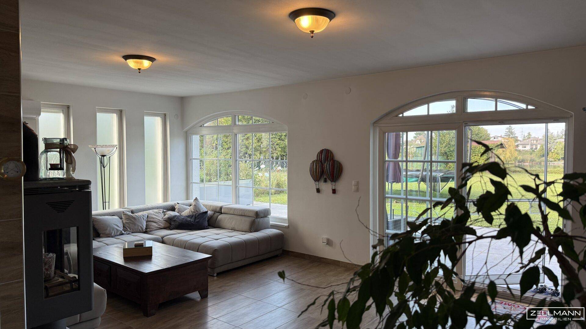 Helles Wohnzimmer mit großen Bogenfenstern, die einen schönen Blick ins Grüne bieten.