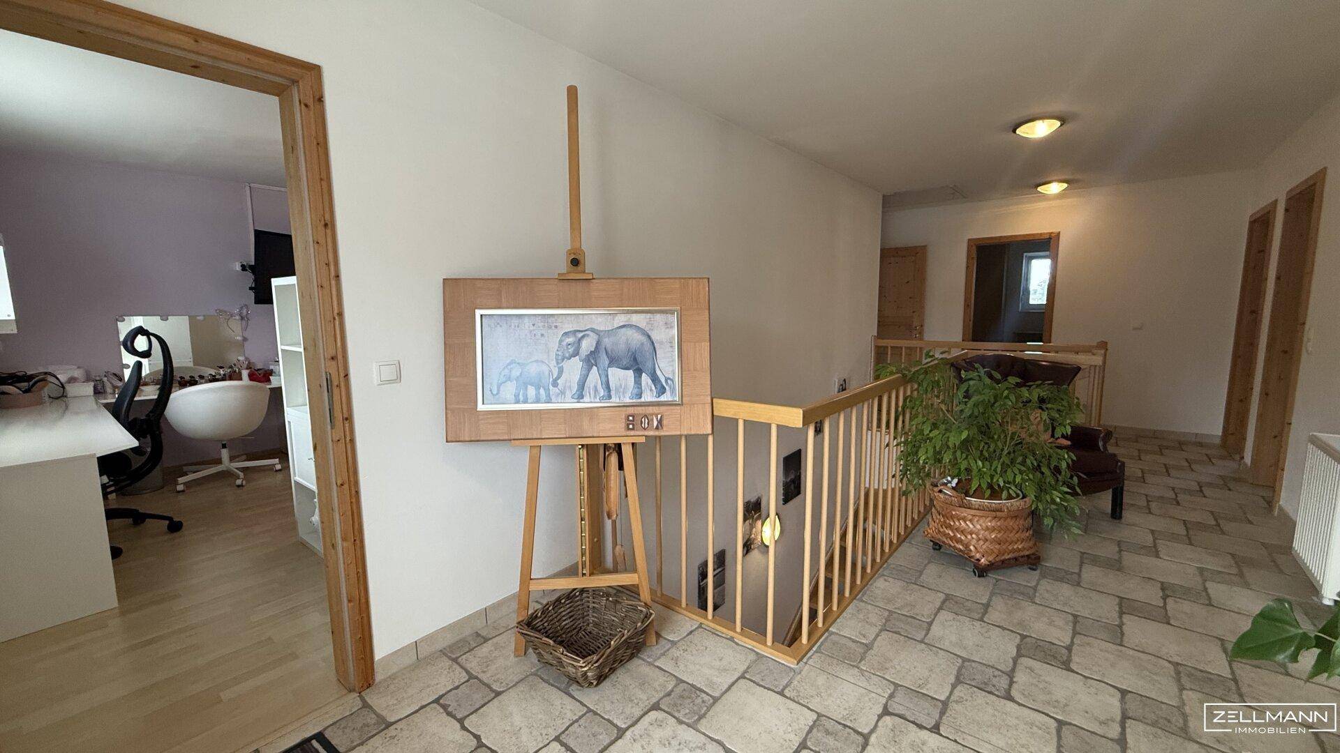 Geräumiger Flur im Obergeschoss mit Blick auf angrenzende Zimmer und hellem Fliesenboden.