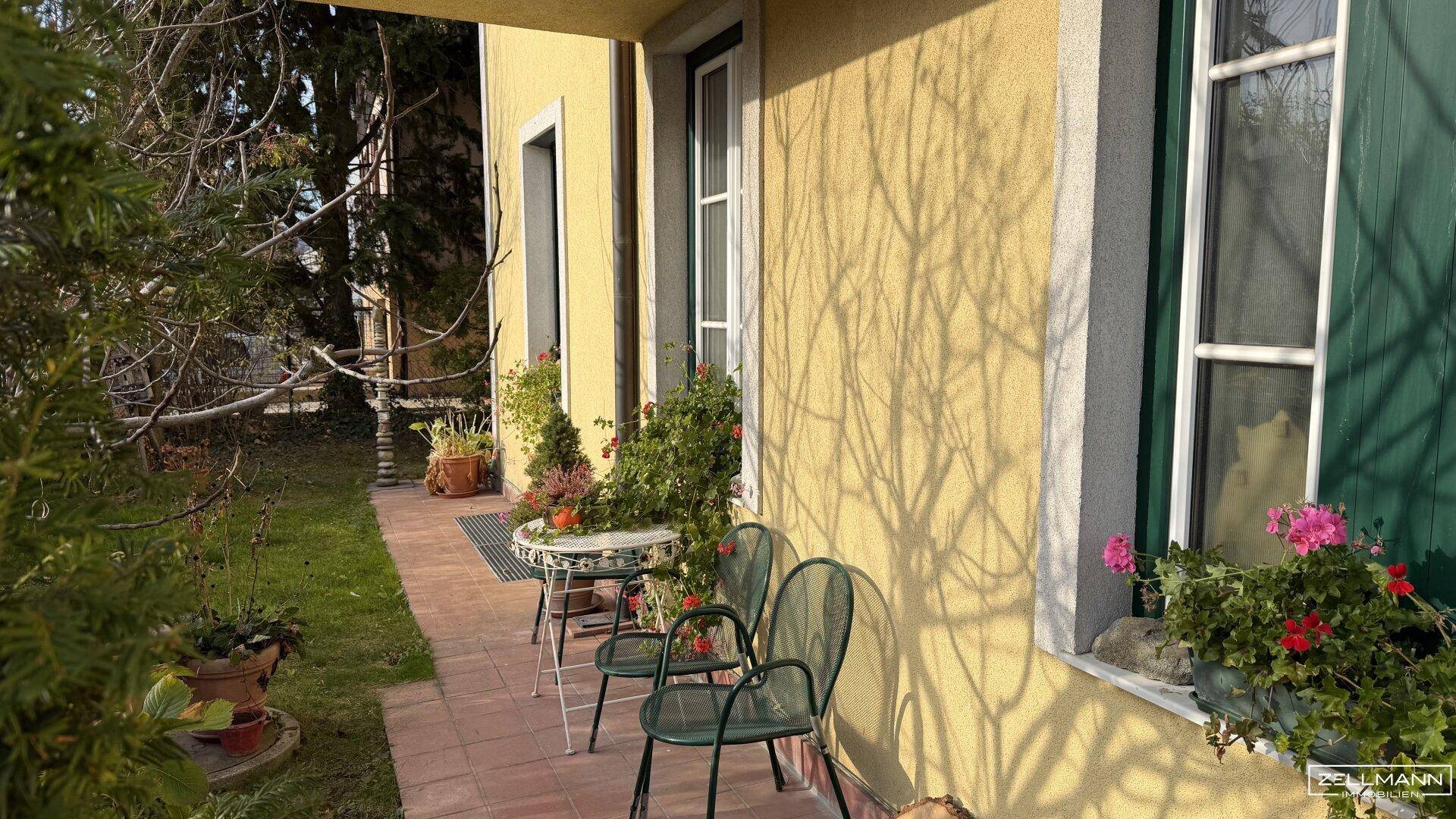 Kleine, gemütliche Terrasse am Haus mit Gartenmöbeln und Blick ins Grüne.