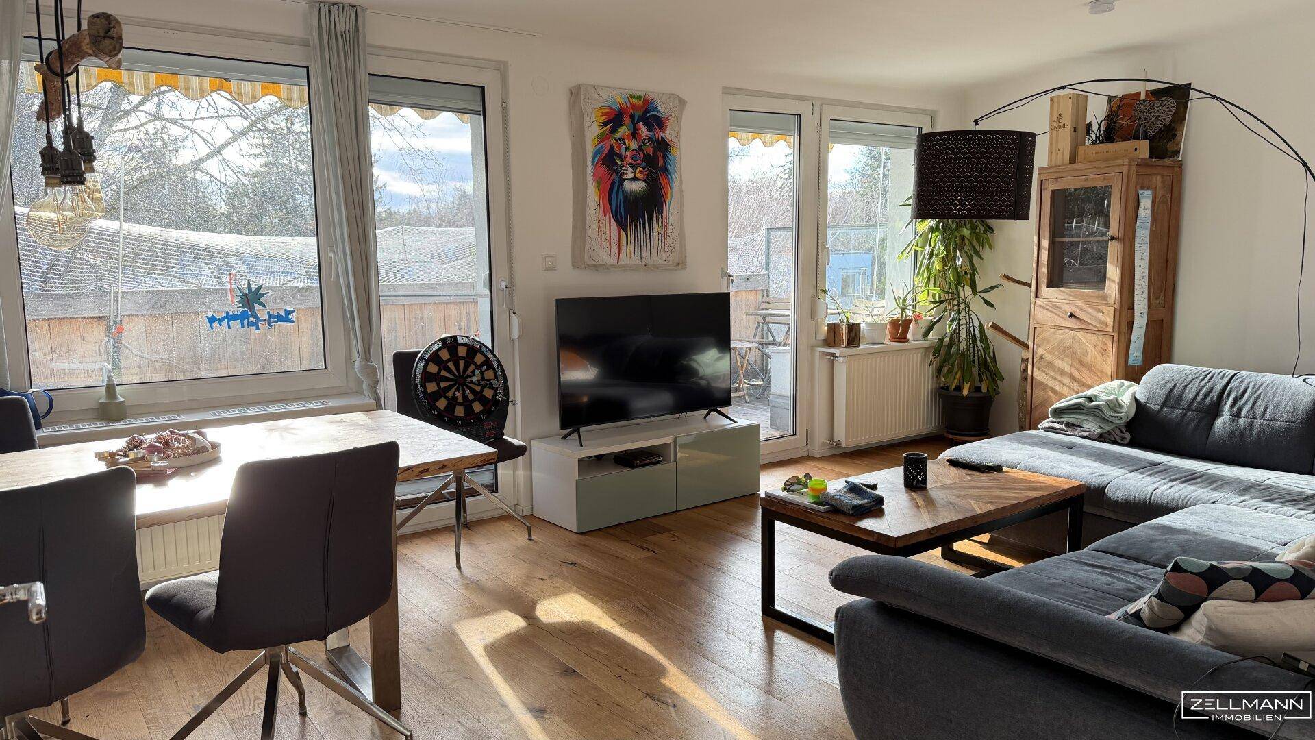 Lichtdurchfluteter Wohn-Essbereich mit modernem Sofa, Holzboden und Zugang zum Außenbereich.