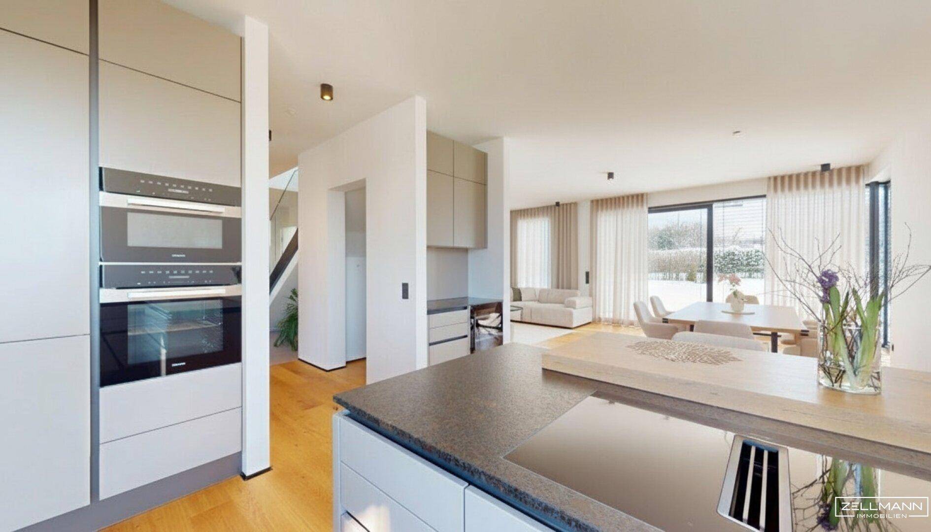 Moderne Küche mit integrierten Geräten und offenem Übergang zum Wohn- und Essbereich.