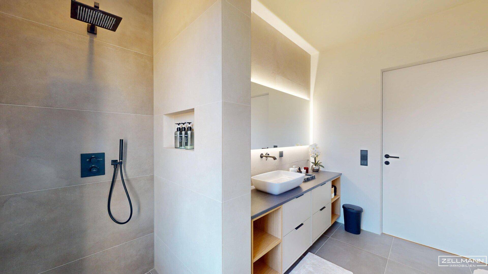 Elegantes Badezimmer mit begehbarer Dusche, Regenbrause und beleuchtetem Spiegelschrank.